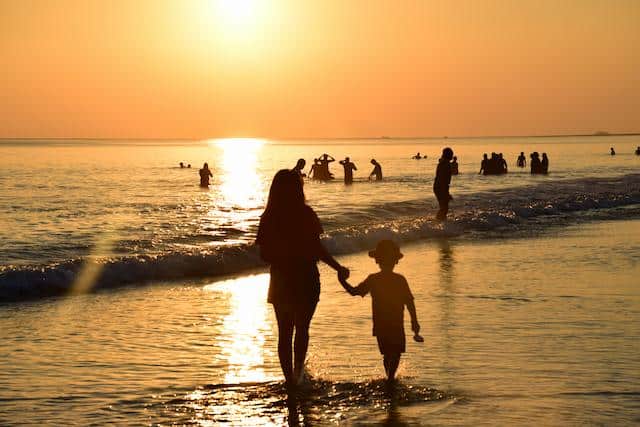 mother-holding-hand-of-baby-sunset-sea